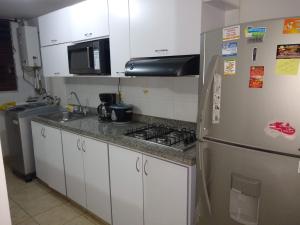 uma cozinha com um frigorífico de aço inoxidável e um micro-ondas em APARTAMENTO VILLA OLÍMPICA em Pereira