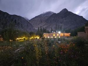 a building in a field with mountains in the background at La Shayok Resort in Nubra