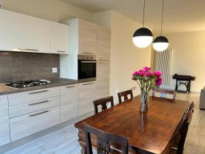 a kitchen with a wooden table with a vase of flowers at Casa Piccolo Charme e Design nel cuore di Maderno in Toscolano Maderno