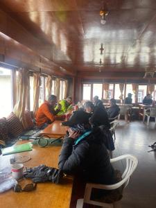 Sherpa Lodge في Lobujya: مجموعة من الناس يجلسون على طاولة في غرفة