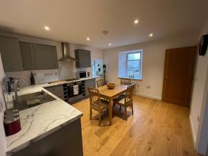 a kitchen with a wooden table and a wooden floor at Alt-Na-Slat Cottage in Invergarry