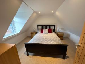 Schlafzimmer im Dachgeschoss mit einem Bett mit roten Kissen in der Unterkunft Alt-Na-Slat Cottage in Invergarry