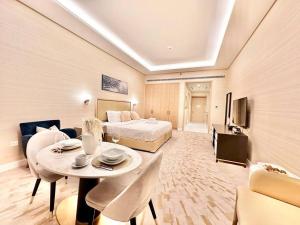 ドバイにあるLuxury Studio in High Floor Full Sea View in The Palm Tower Plam Jumeirahのベッド、テーブル、椅子が備わるホテルルームです。