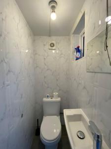 Baño blanco con aseo y lavamanos en Queen's Cottage en Hendon
