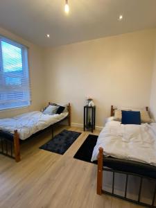 1 dormitorio con 2 camas y ventana en Queen's Cottage, en Hendon