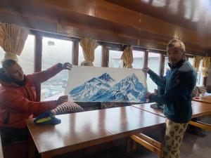 duas pessoas a segurar um quadro numa mesa em Sherpa Lodge em Lobujya