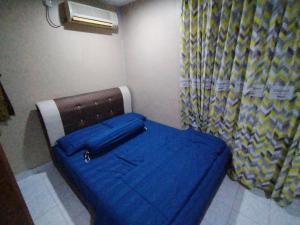 Cette petite chambre comprend un lit avec une couverture bleue. dans l'établissement zam homestay kulim perdana hitech utk Msliim shj, à Kulim