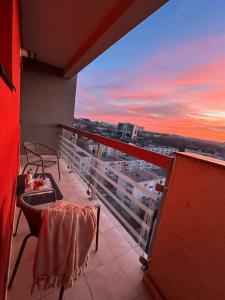 d'un balcon avec une table et des chaises et un coucher de soleil. dans l'établissement Panoramic Sunrise near IULIUS MALL by cityZen Suites, à Iaşi