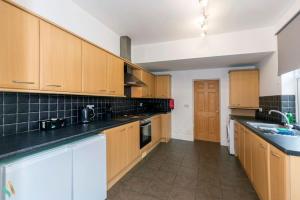 una cocina con armarios de madera y encimeras negras en Pine House, en Stockton-on-Tees