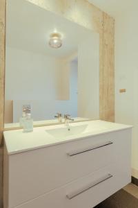 ein Badezimmer mit einem weißen Waschbecken und einem Spiegel in der Unterkunft Downtown - Retro Decor - Stunning Views - Terrace in Tórshavn