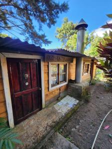 ein kleines Haus mit einer Tür und einem Kamin in der Unterkunft Residencial El Cielo Cabaña Popeye y Cabaña Pipil in Los Naranjos