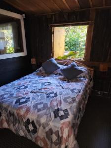 a bed with pillows in a room with a window at Residencial El Cielo Cabaña Popeye y Cabaña Pipil in Los Naranjos