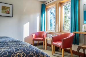 a hotel room with two chairs and a bed and windows at Crubenbeg Country House in Newtonmore