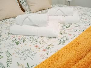 een bed met witte handdoeken en bloemen erop bij Moderno estudio en la playa de las Canteras in Las Palmas de Gran Canaria