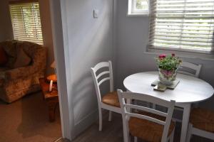 a white table and chairs with a vase of flowers on it at Lovely Garden Cottage in Snettisham in Snettisham