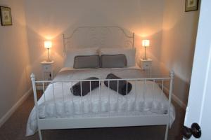a bedroom with a white bed with two lamps at Lovely Garden Cottage in Snettisham in Snettisham