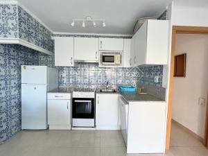 カンブリルスにあるApartamento en primera linea de playa 100A - INMO22の白い家電製品と青い壁紙が備わるキッチン