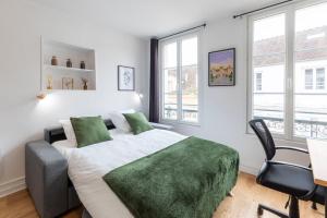 a bedroom with a bed and a desk and windows at Cœur de Fontainebleau: Confort, Calme & Haut débit in Fontainebleau