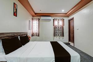 een slaapkamer met een groot wit bed en 2 ramen bij OYO Sri Sai Sevalal Comfort's in Bangalore