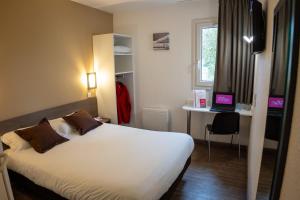 a hotel room with a bed and a desk with a laptop at Fasthôtel Périgueux in Marsac-sur-lʼIsle