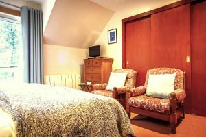 1 dormitorio con 2 sillas, 1 cama y TV en Crubenbeg Country House, en Newtonmore