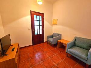 a living room with two chairs and a television at Casa do Castelo III in Arraiolos
