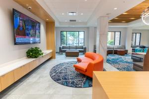an office lobby with an orange chair and a large screen at Hampton Inn Knoxville-West At Cedar Bluff in Knoxville