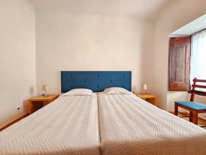 a bedroom with a large bed with a blue headboard at Casa do Castelo III in Arraiolos