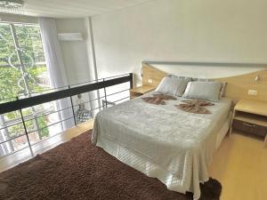 1 dormitorio con cama grande y ventana grande en Saint Sebastian Flat 603- Com Hidro! até 3 pessoas, Duplex, no centro en Jaraguá do Sul