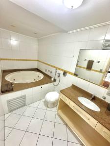 y baño con bañera, aseo y lavamanos. en Saint Sebastian Flat 603- Com Hidro! até 3 pessoas, Duplex, no centro, en Jaraguá do Sul
