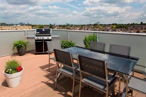 een balkon met een tafel en stoelen op een dak bij Madison Hill - White Hill House 5 - 3 bedroom flat in Londen