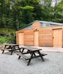 two picnic tables in front of a wooden building at Ghyll Shepherd's Hut in Rydal