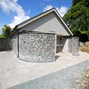 a house with a stone wall and a garage at Ghyll Shepherd's Hut in Rydal