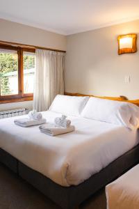 1 dormitorio con 1 cama grande y toallas. en Hostería y Cabañas Quime Quipan by Nordic en San Carlos de Bariloche