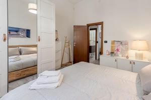 a white bedroom with a bed and a mirror at Nel cuore del rione del Drago in Pistoia