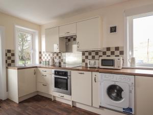 a kitchen with white cabinets and a washer and dryer at Taigh Neilag in Elgol