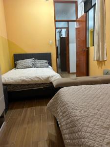 a bedroom with two beds and a door to a room at Departamento interior 1er piso. in Cajamarca