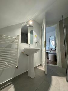 a white bathroom with a sink and a shower at Pensiunea Korona and Restaurant in Miercurea-Ciuc