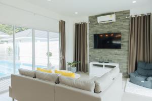 a living room with a white couch and a tv at Private 3BR Pool House Near Pattaya Beach in Ban Huai Yai