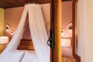 1 dormitorio con cama con dosel y espejo en Carícia do Vento Pousada Boutique, en Monte Verde