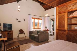 ein Schlafzimmer mit einem Bett, einem Sofa und einem TV in der Unterkunft Carícia do Vento Pousada Boutique in Monte Verde