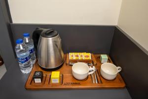 bandeja de madera con cafetera, tazas y agua en İstanbul Hotel & Suites, en Estambul
