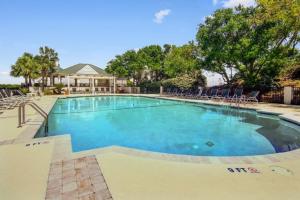 a large swimming pool with chairs and a house at Pure Joy by AvantStay Beach Home w Amazing Views Community Pool in Isle of Palms