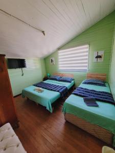a room with three beds and a tv in it at Hostal Paradise Blue in Osorno