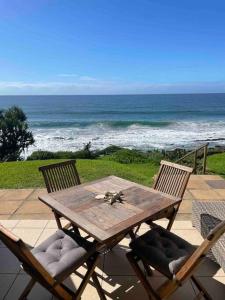une table et des chaises en bois avec l'océan en arrière-plan dans l'établissement Modern and Stylish beach pad with Stunning Ocean View, à Ballito