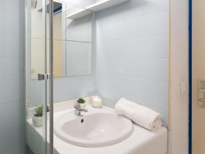 une salle de bains blanche avec un lavabo et un miroir dans l'établissement Apartment Les Flamants Roses-1 by Interhome, à La Grande Motte