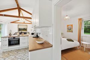 una cocina con armarios blancos y una cama en una habitación en Idylisches Cottage mit Reh, en Wörthsee