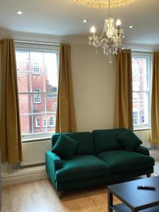 a living room with a green couch and a chandelier at Aachen Hotel in Liverpool