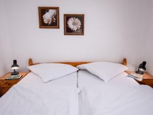 2 weiße Betten in einem Schlafzimmer mit 2 Bildern an der Wand in der Unterkunft Apartment Küstennebel by Interhome in Norddeich