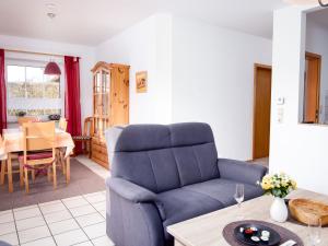 ein Wohnzimmer mit einem blauen Stuhl und einem Tisch in der Unterkunft Apartment Küstennebel by Interhome in Norddeich